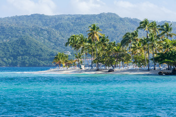 Beach landscape with sand, white foam waves, palm trees, blue sky, turquoise water and clouds, paradise Caribbean coast of Dominican republic 