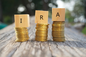 Close up of stacking gold coins and wooden blocks written IRA on nature background and natural...