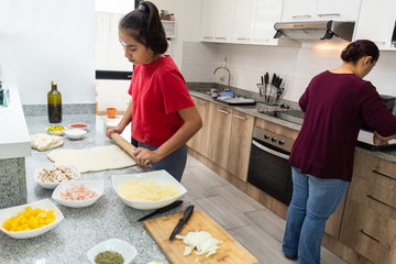 A mother with her daughter preparing pizza in the kitchen