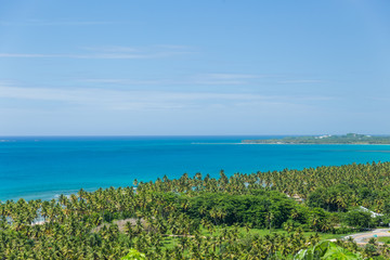 Beach landscape with sand, white foam waves, palm trees, blue sky, turquoise water and clouds, paradise Caribbean coast of Dominican republic 