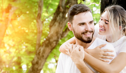 Fototapeta premium Happy young caucasian couple embracing together with passionate love in public park,Couple in love hugging and having romantic tender moments in the summer vacation.Lifestyle loving couple at nature.
