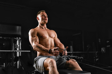 Fototapeta na wymiar Fit and muscular man trains chest muscles on a block simulator in a gym. An ideal fitness model, trained in the gym. Sport banner, copy space, fitness motivation.