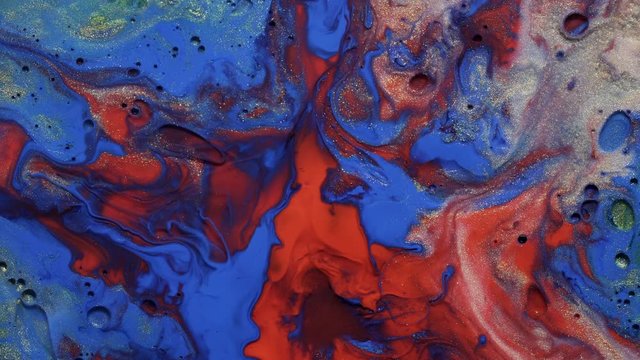 Colorful background in motion. Gold dust blue and red paint flow on universe colors surface mix in fantastic design and patterns. Sparkling particles, ink drops and mixing. Multicolored liquid