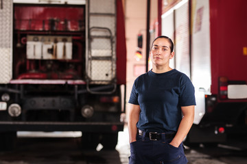 Professional fireman portrait. Female firefighter wearing uniform of shirt and trousers. Fire truck...