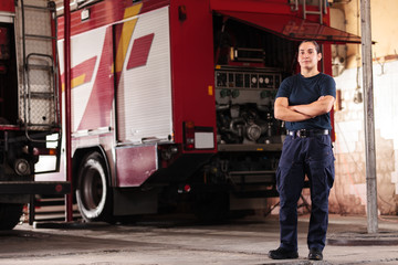 Professional fireman portrait. Female firefighter wearing uniform of shirt and trousers. Fire truck in the background.