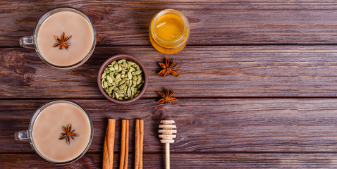 Glass cups of traditional indian chai masala tea on a tray with ingredients