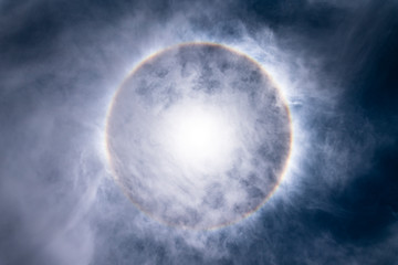 The Sun, with an amazing halo around the sun created by light refraction because of ice crystals on the upper atmosphere layers in the troposphere that create this circumscribed circular sun halo
