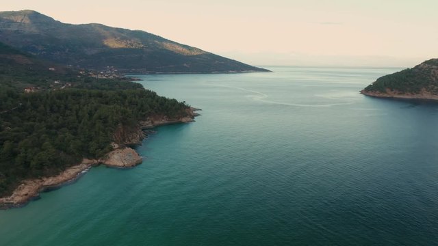 Drone flight around the mountain slopes and rocky coastline of Thasos island and the little island Nisida Kinira, Greece