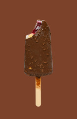 chocolate outer popsicle with blueberry sauce inside with a bite on brown background