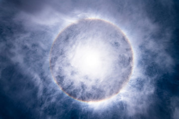 The Sun, with an amazing halo around the sun created by light refraction because of ice crystals on the upper atmosphere layers in the troposphere that create this circumscribed circular sun halo
