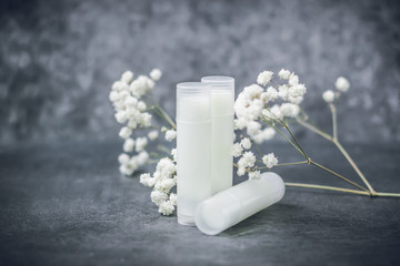 lip balm with flowers in a transparent tube with white contents. DIY lipstick made from natural...