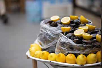 Stuffed mussels close-up on the street. Traditional Mediterranean appetizer. Next to the mussels, there are lemons. Close up.