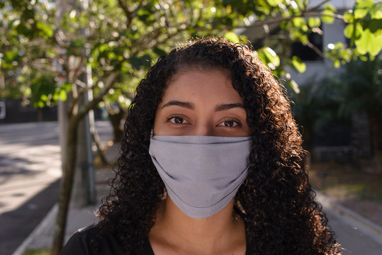 Black woman on urban background in casual clothing wearing a protective medical mask