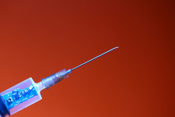 Syringe with a chip on a red background, toned. The concept of the theory of conspiracy and...