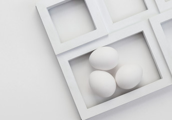 Three white eggs in a rectangular frame on a white background.