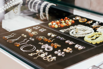 Behind glass jewelry on a black box. Earrings, bracelets, ring. Yellow and brown stones. Diamonds, topazes, jasper. Glamor