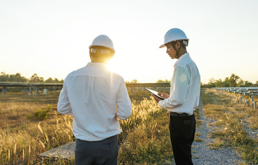 The solar farm(solar panel) with two engineers walk to check the operation of the system,...