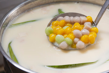 Thai sweetmeat call Bualoy balls in dippers with hot coconut milk in a pot and leaf pandan increase delicious
