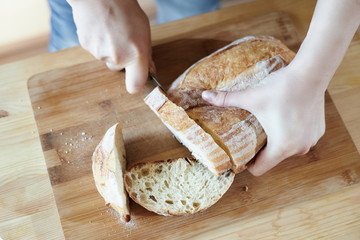 slicing bread with a knife on a wooden board at home step 1