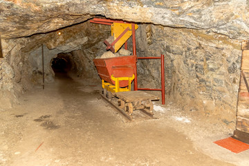 Fototapeta na wymiar Red Cart with stones in a tunnel of a gold mine 