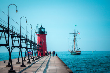 Tall ship sailing past a light house