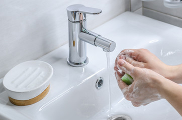 Hand washing with soap. Preventive measures against infection. A young guy washes his hands with...