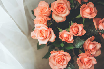 bouquet of pink bright roses on a wooden table with white curtains on the background