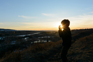 Fototapeta premium silhouette of a young boy standing on a hill