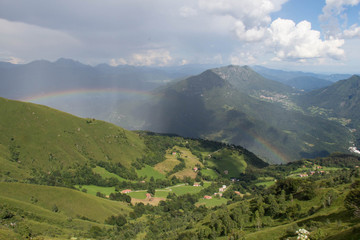 Picturesque landscape with rainbow over mountains in a sunny day.