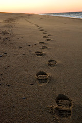 Footprints in the sand on beach at sunset