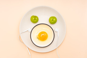 Eggs, green plums, headphones are placed in the shape of a smiling face