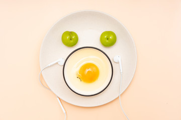 Eggs, green plums, headphones are placed in the shape of a smiling face