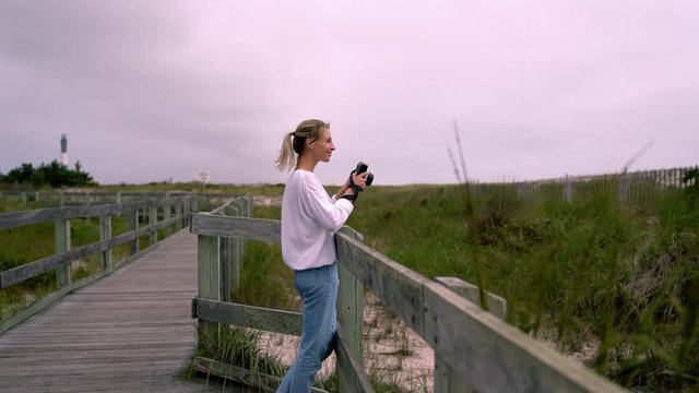 Happy caucasian female tourist feeling excited from spending leisure time at nature for photography hobby. Smiling hipster girl focusing while taking images on instant camera in vacations. slow motion