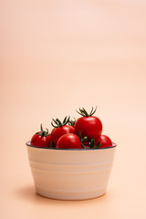 Bowl filled with cherry tomatoes and small tomatoes on orange background