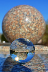 Transparent glass crystal ball on the marble surface with reflection marble sphere inside close up. Blurred background