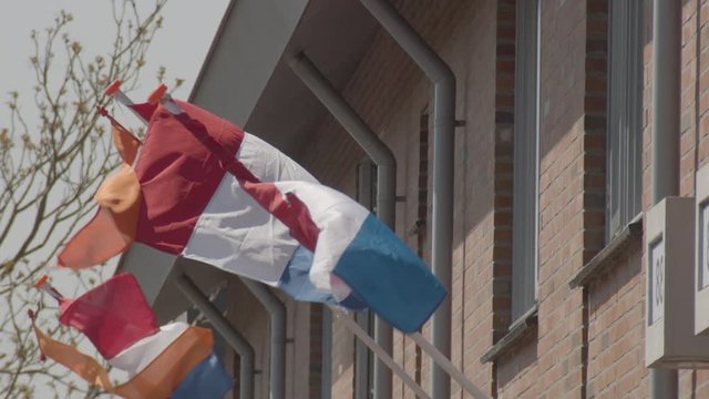 Panning over Dutch flags hanging on houses in suburban neighborhood - slow motion