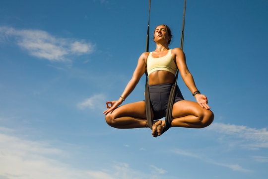 acroyoga meditation beach workout - young attractive and healthy woman practicing aerial acro yoga training balance body and mind control hanging above the sea
