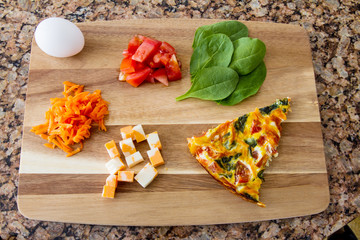 Omelette with the fresh ingredients of egg, cheese, carrots, tomatoes and spinach; fresh ingredients to create a small omelette