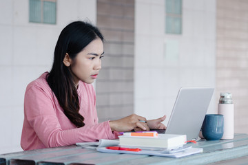 Portrait of a young Asian female adult learner stuying online at home during Coronavirus or COVID-19  pandemic. Businesswoman work with laptop at home in hous corridor and garden