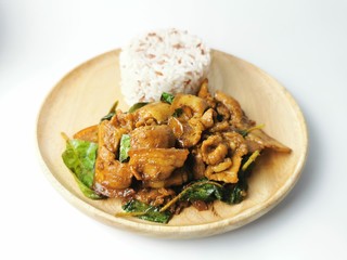 Stir fried bacon with basil and three color rice in a wooden plate on white background 