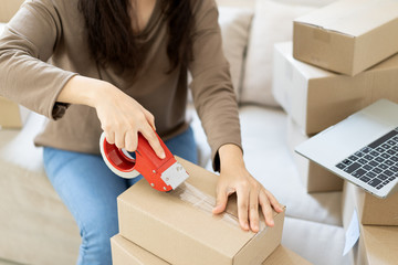 Close-up asian woman hand packing cardboard boxes. House moving  or Online shop activity concept. .