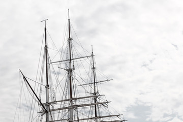 Elaborate rigging on a three mast tall ship against a gray sky, horizontal aspect