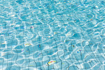 Sun reflection in clear clean and bright blue water of swimming pool, Shining blue water ripple background, Aqua texture, pattern