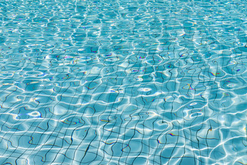 Sun reflection in clear clean and bright blue water of swimming pool, Shining blue water ripple background, Aqua texture, pattern