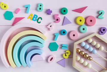 Wooden toy rainbow, numbers, blocks, pastel color arc on pink background. Natural no plastic toys for creativity development. Flat lay, top view. Educational games for kindergarten, preschool kids