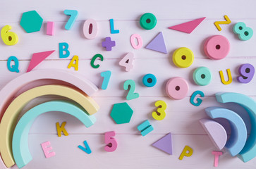 Wooden toy rainbow, numbers, blocks, pastel color arc on pink background. Natural no plastic toys for creativity development. Flat lay, top view. Educational games for kindergarten, preschool kids