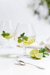 Cocktail mojito decorado con limas, limones y mentas. Sobre fondo blanco.