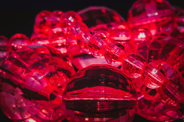 
red oval beads with faces and a pattern inside on a black texture background