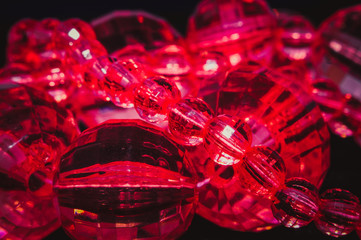 
red oval beads with faces and a pattern inside on a black texture background
