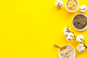 Set of cosmetic clays for facial beauty face mask on yellow table top-down frame space for text